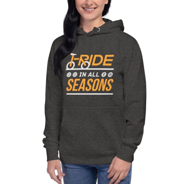 Young woman wearing premium hoodie in charcoal heather with text "I ride in all seasons" and small seasons icons