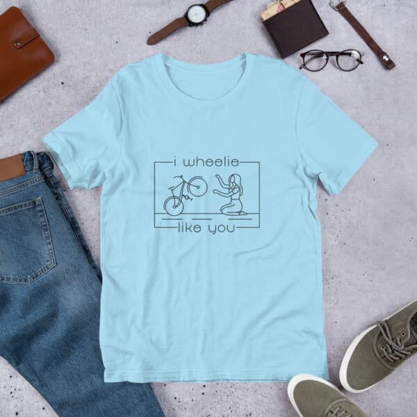 Unisex staple t-shirt in ocean blue with a bike and girl about to embrace with text "I wheelie like you"