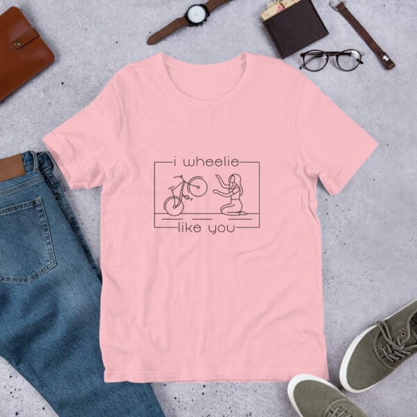 Unisex staple t-shirt in pink with a bike and girl about to embrace with text "I wheelie like you"