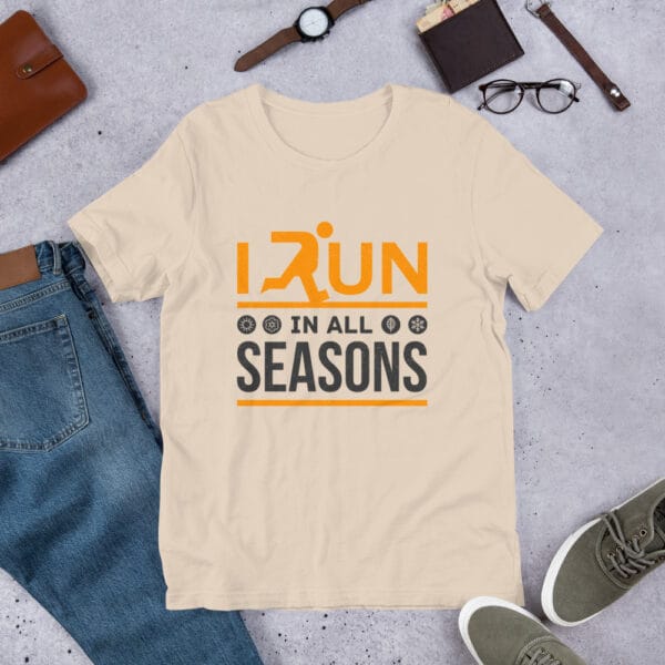 Unisex staple t-shirt in soft cream with text "I run in all seasons" with the letter R a silhouette of a runner