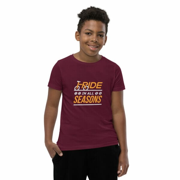 Young boy wearing a maroon staple t-shirt with text 'I ride in all seasons'