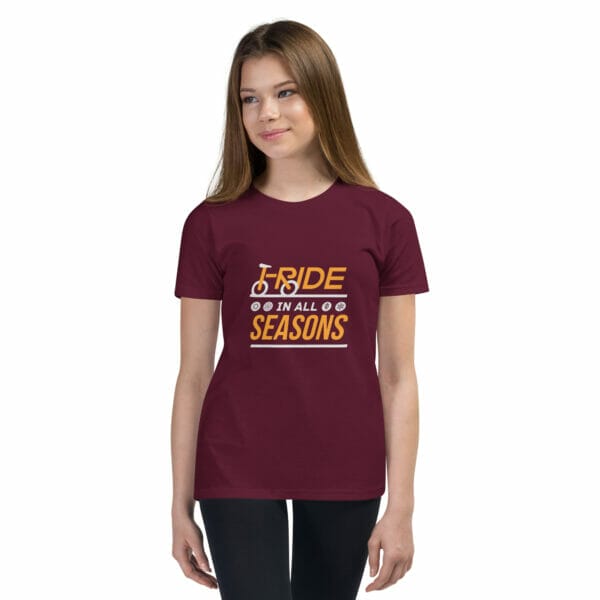 Young girl wearing a maroon staple t-shirt with text 'I ride in all seasons'