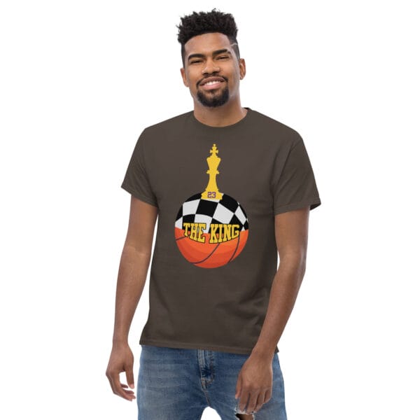 Man wearing classic tee in dark chocolate with text 'The King', a basketball with top half a chess board and King piece on top with number 23