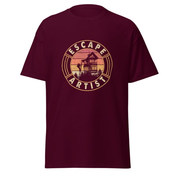 Men's classic tee in maroon showing a golfer climbing down ladders from top floor of home with text 'Escape Artist'