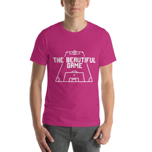 Man wearing a staple t-shirt in berry with white text 'The Beautiful Game' inside a football pitch