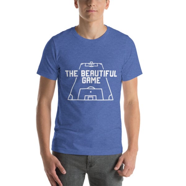 Man wearing a staple t-shirt in heather true royal with white text 'The Beautiful Game' inside a football pitch