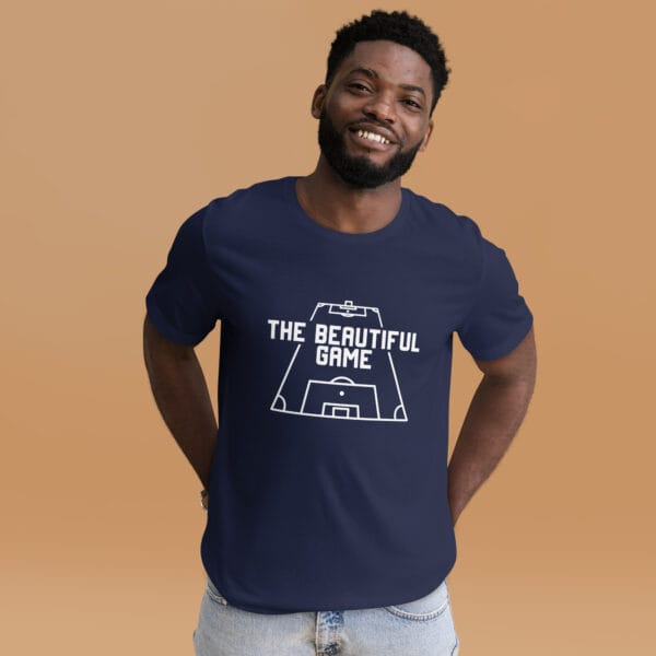 Man wearing a staple t-shirt in navy with white text 'The Beautiful Game' inside a football pitch