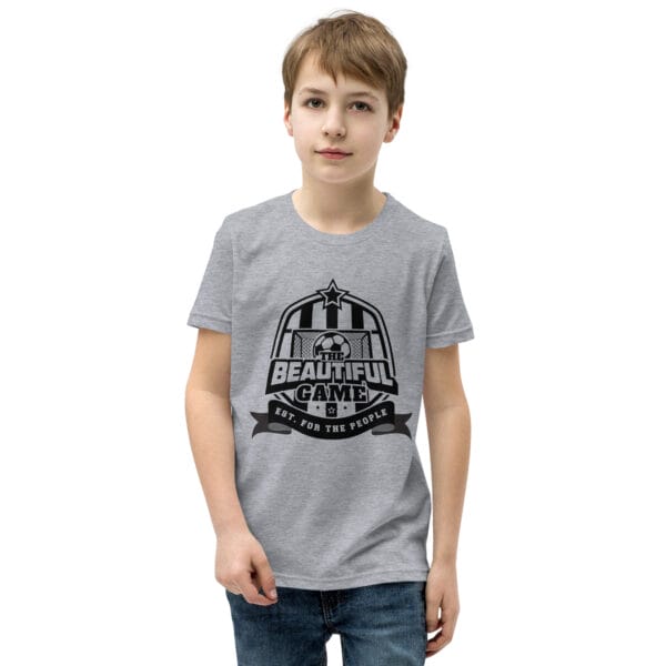 Boy in an athletic heather staple t-shirt with a black The Beautiful Game crest, est. for the people