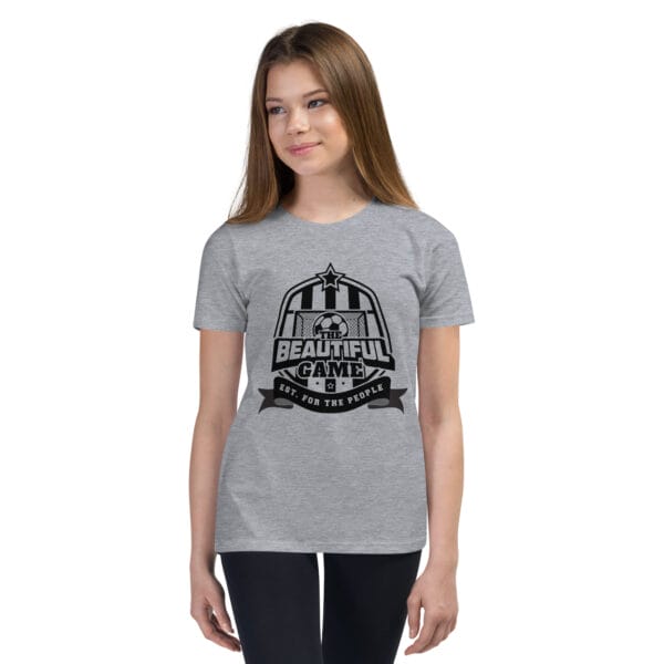 Girl in an athletic heather staple t-shirt with a black The Beautiful Game crest, est. for the people