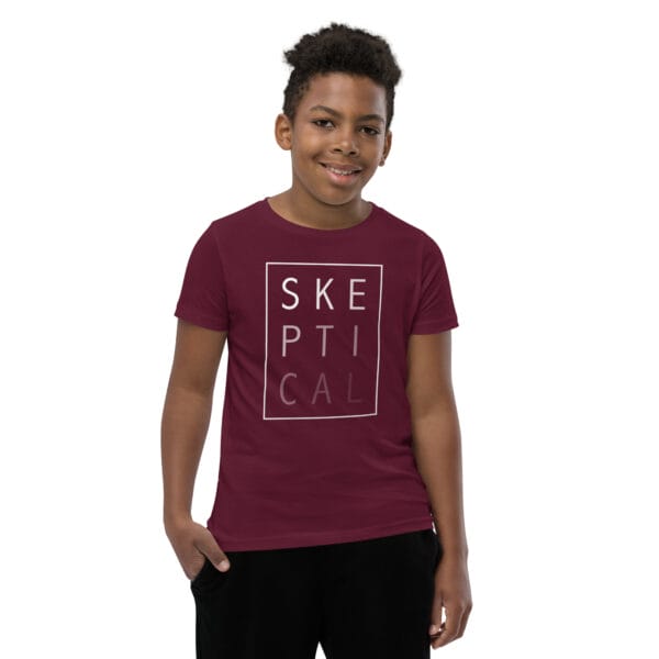 Boy wearing a maroon staple t-shirt with white text 'SKEPTICAL' fading out inside a box