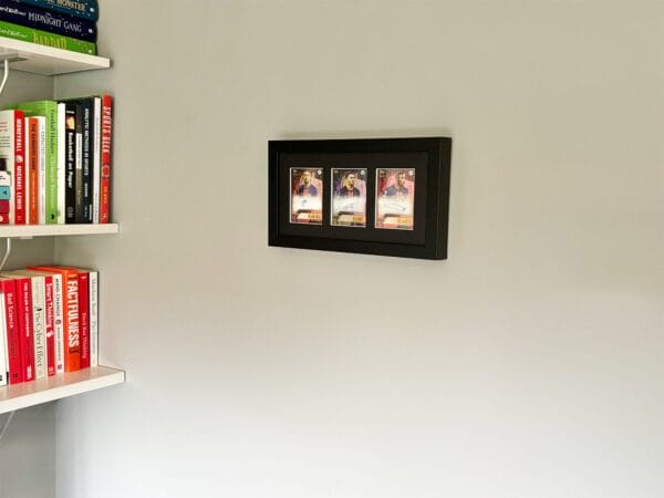 PSG memorabilia black display with Barcola, Ramos and Dembele autographs hanging up on a wall next to shelves