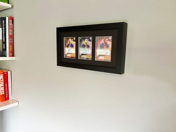 PSG memorabilia black display with Barcola, Ramos and Dembele autographs hanging up on a wall next to shelves