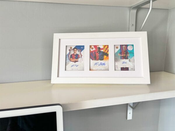 Barcelona 125th Anniversary memorabilia display, white frame, three signed sports cards from Victor, Rivaldo and Olmo, on shelf