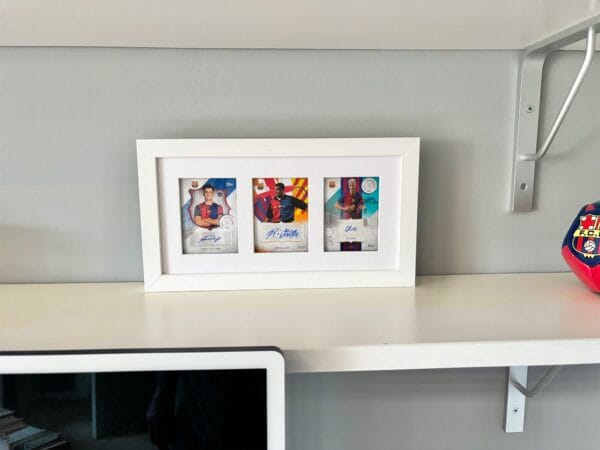 Barcelona memorabilia display, white frame, standing upright on shelf, three autographs from Victor, Rivaldo and Olmo