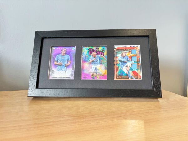 Erling Haaland autograph and relic display, black frame standing on bedside table holding three sports cards