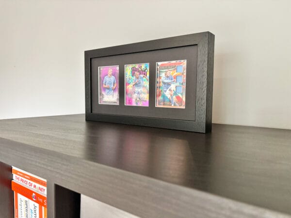 Erling Haaland memorabilia display standing upright, black frame holding three sports cards, with Haaland autograph