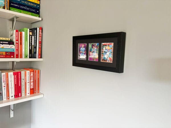 Erling Haaland autograph and relic display hanging on wall, black frame holding three sports cards