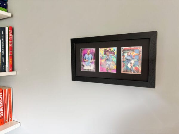 Erling Haaland autograph and relic display hanging on wall, black frame holding three sports cards
